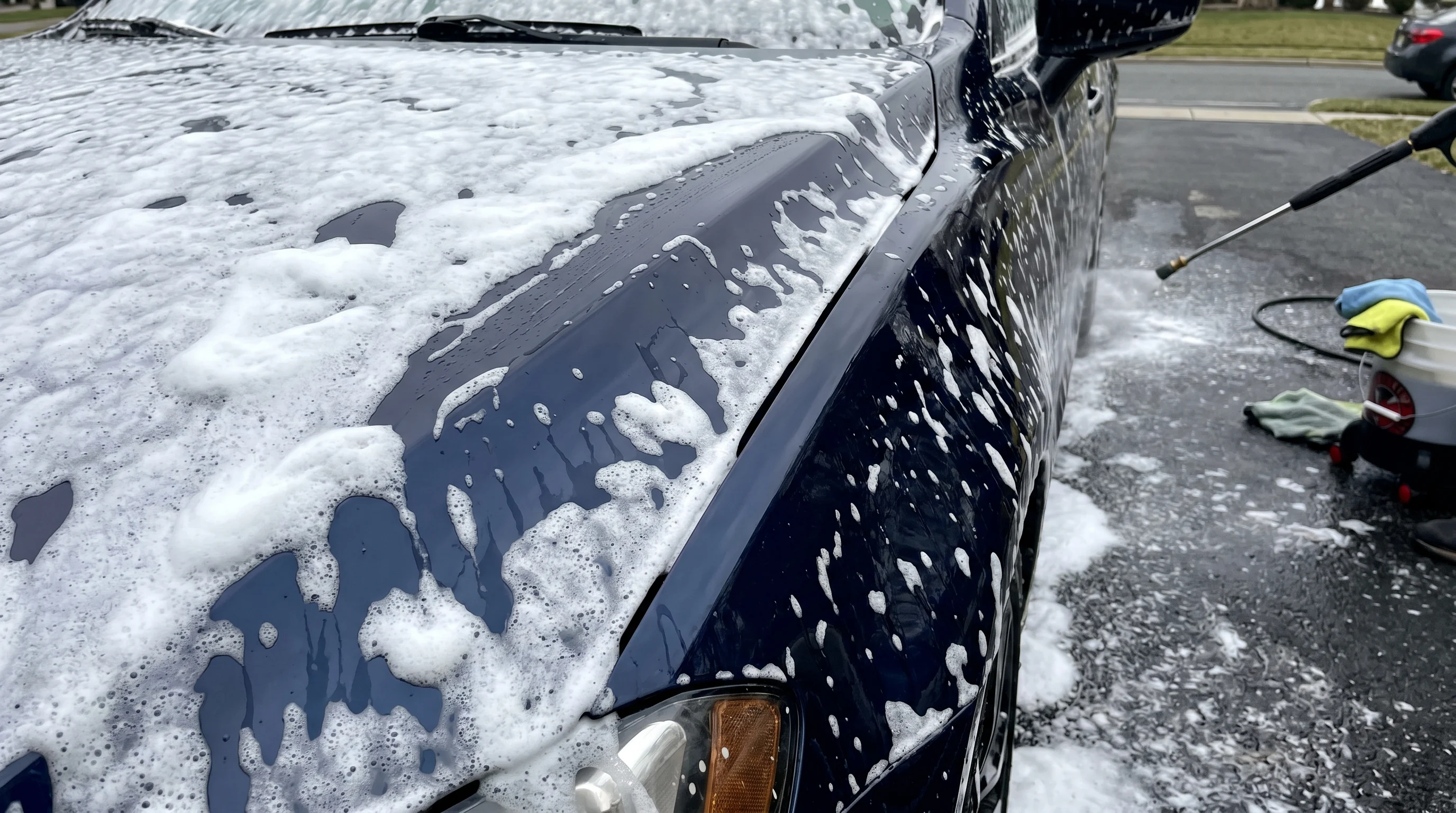 gęsta biała piana snow foam pokrywająca karoserię auta przed myciem